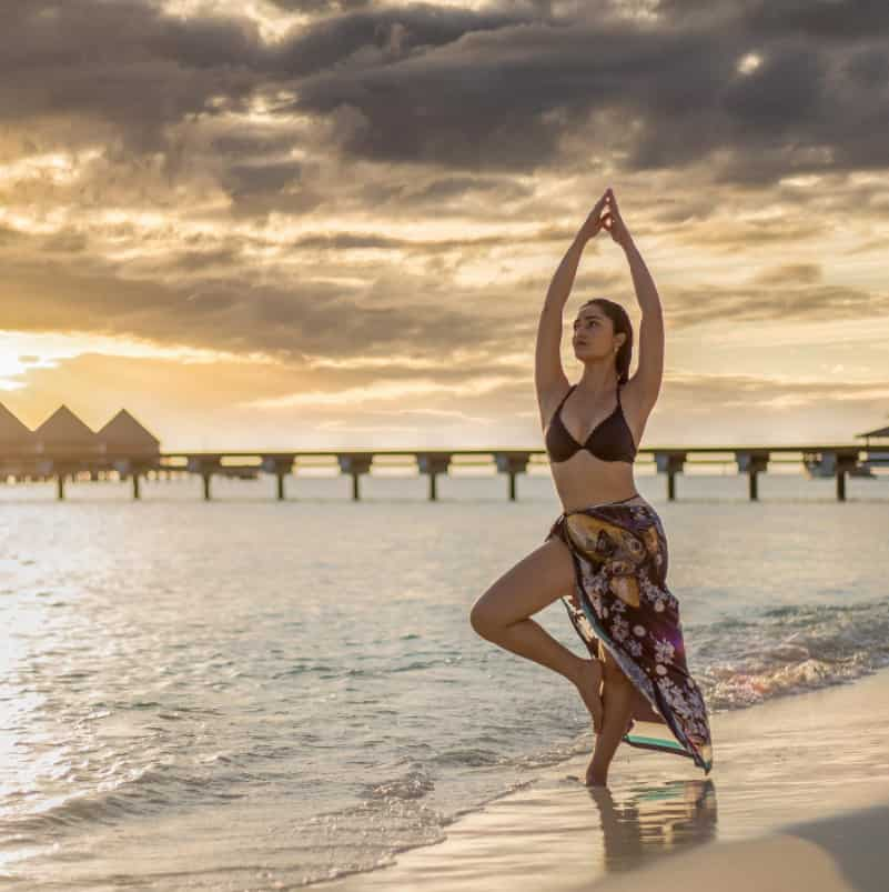 The Aashram actress seems stunning in her brown bra and printed wrap beside the beach.